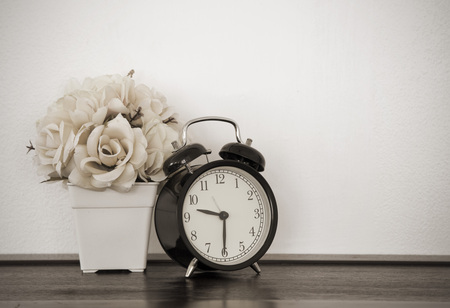 Artificial plastic flowers and clock on table