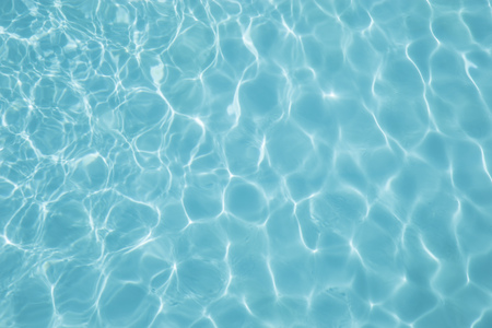 Blue swimming pool reflecting the sun rippledの写真素材