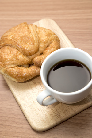 Coffee and croissant on wooden background on the tableの写真素材