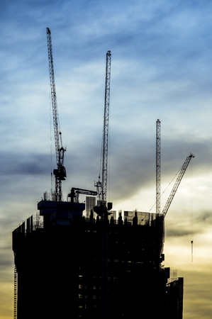 Construction of building with tower cranes against skyの写真素材