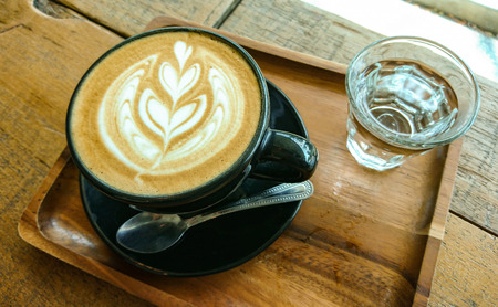 Hot latte coffee with water on tableの写真素材
