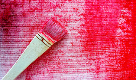 Paint brush with red color on canvas backgroundの写真素材