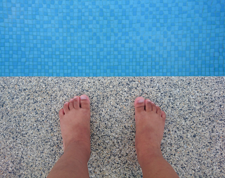 Child feet standing on side swimming poolの写真素材