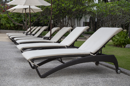 Beach chairs and umbrella beside swimming pool in hotelの写真素材