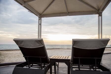 Sunset with empty beach chairs near seaの写真素材