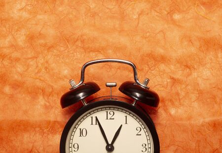 Black clock on orange color paper backgroundの写真素材