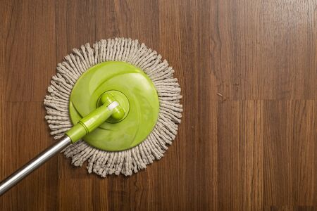 Cleaning wooden floor with old green mop