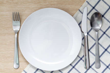 Empty plate with napkin and silverware over wooden tableの写真素材