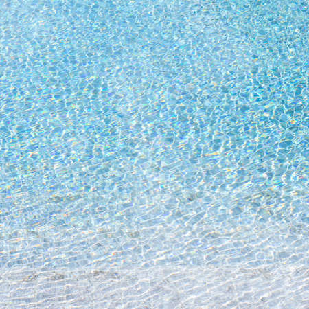 Blue swimming pool reflecting the sun rippledの写真素材