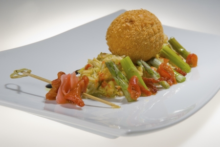 round chicken cutlet with red fish and asparagus on a white rectangular  platterの写真素材