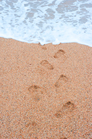footprints  sand leading into  sea rhythmically stretchingの写真素材