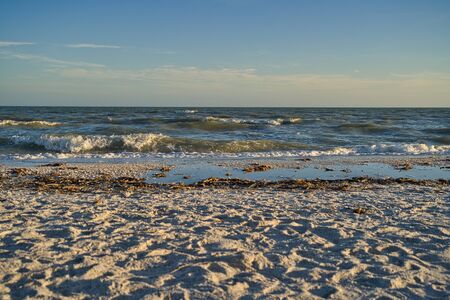 Spray and foaming waves on the lonely natural beach during sunsetの写真素材