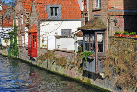 Old houses on the banks of a river channel in Bruges, Belgiumの写真素材