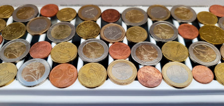 The concept of high cost of heating and electricity and the possibility of an early onset of an energy crisis. There are many euro coins of different denominations on the heating radiatorの写真素材