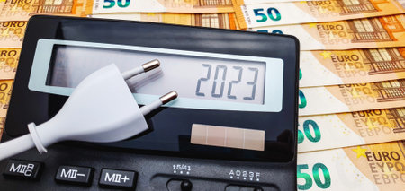 Electric plug and calculator on the background of a large number of 50 euro banknotes. The concept of high cost of electricity, inflation and crisis in 2023の写真素材