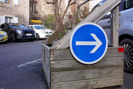 Blue circular direction arrow road sign on a rustic wooden planter in city street