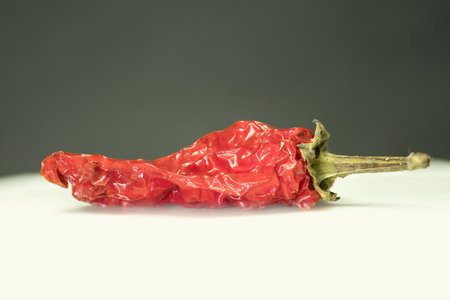 Aged Elegance: The Vivid Texture of a Wrinkled Red Chili Pepper, This image features a single, aged...