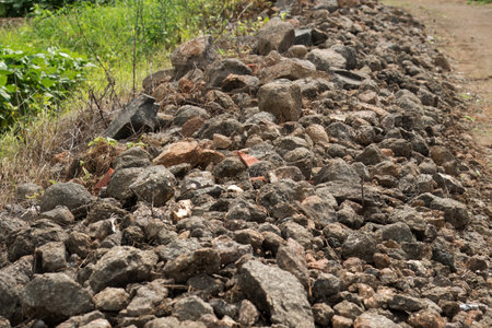 A large pile of rocks is situated beside the road, creating a natural barrier along the roadside landscapeの写真素材