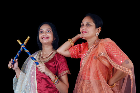 In preparation for the vibrant Navratri festival, two women are seen rehearsing their Dandiya dance moves with great enthusiasm and care. Dressed in traditional attire, they hold their beautifully decorated dandiya sticks, practicing each step with precision and joy. The rehearsal captures the essence of dedication and the cultural significance of Dandiya Raas, a dance form that celebrates the divine feminine energy and the spirit of togetherness. The rhythmic clashing of the sticks and their synchronized movements reflect the harmony and excitement that the festival brings.の写真素材