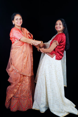 A beautiful Indian mother and her daughter are participating in the traditional folk dance of...