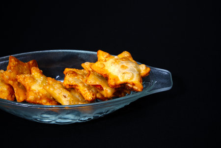 A glass bowl filled with crispy fried potato snacks, beautifully arranged and ready to be served.の写真素材