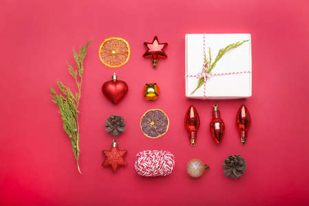 Christmas composition. Christmas red decorations, fir tree branches, gift on red background. Flat layの写真素材