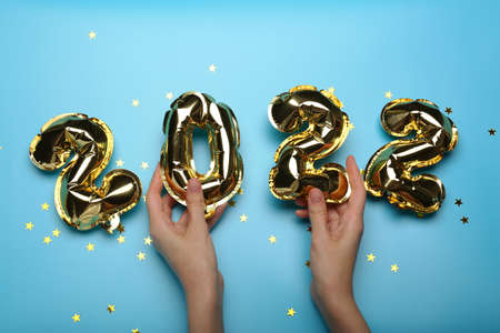 golden balloons in hands on a blue background 2022. New year conceptの写真素材