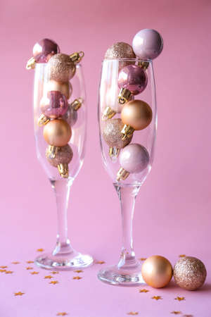 christmas decorations in champagne glasses on pink background. new year conceptの写真素材