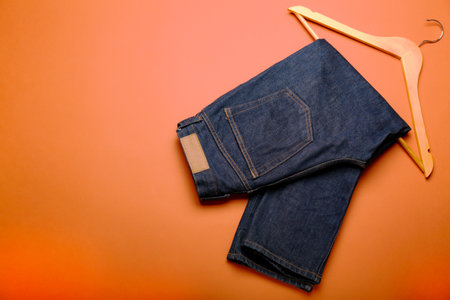 flat lay blue jeans with a wooden hanger on a orange background.の写真素材