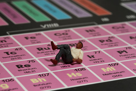 Miniature people : Businessman sitting on the periodic table of chemical elements