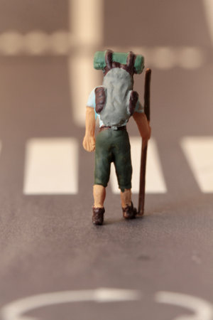Miniature people : A man with a stick in his hand walking on a roadの写真素材