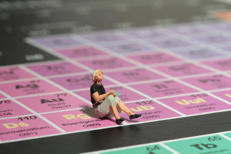 Miniature people : woman sitting on the periodic table of chemical elements. Image use for school...