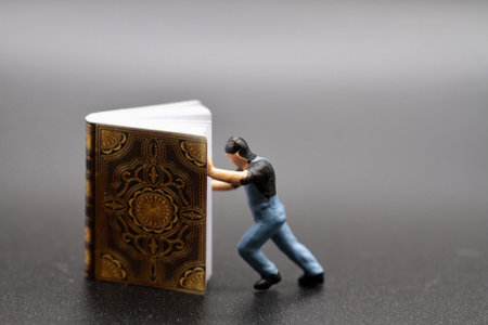 Miniature people : man pushing a book on black background.の写真素材