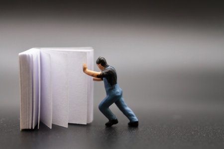 Miniature people : man pushing a book on black background.の写真素材