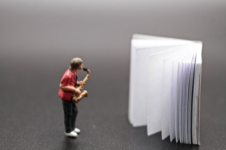 Miniature people: sax player reading music on the book.の写真素材