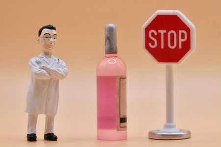 Miniature people : Doctor and stop sign on pastel background with a bottle of wineの写真素材