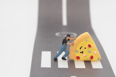 Miniature people : delivery man pushing a giant slice of pizza on the road