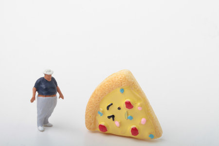 Miniature people : A fat man and a slice of pizza on white backgroundの写真素材