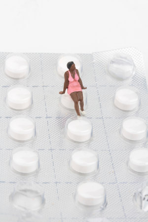 Miniature people, woman sitting on a blister pack of pills.の写真素材