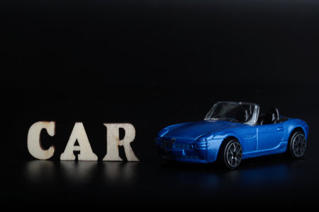 Car insurance concept. Toy car and wooden letters on black background.の写真素材