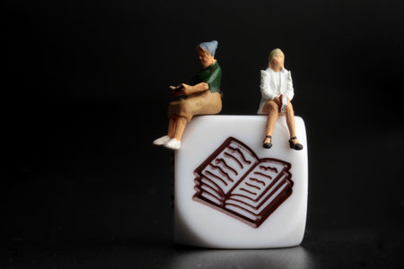 miniature people reading a book on a black background with copy spaceの写真素材