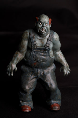 A close up shot of a plastic zombie figure on a black background