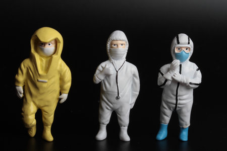 Miniature people wearing hazmat suit and face mask on black backgroundの写真素材