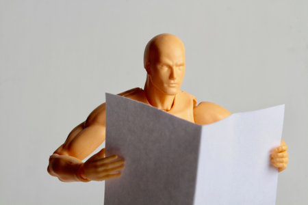 Plasticine mannequin reading a newspaper on a white backgroundの写真素材