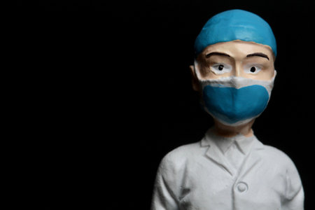 Plasticine surgeon with face mask on black background with copy space