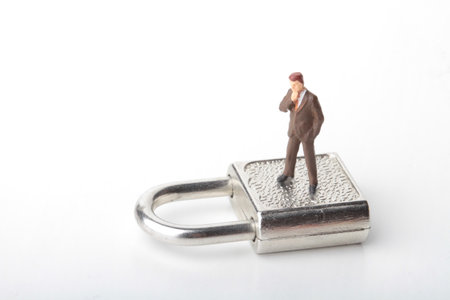 Miniature people: Businessman standing on padlock on white background.の写真素材