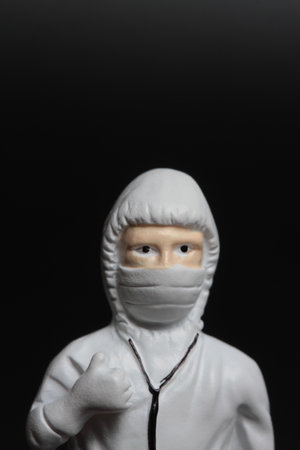 White plastic figure of a man in a medical mask on a black backgroundの写真素材