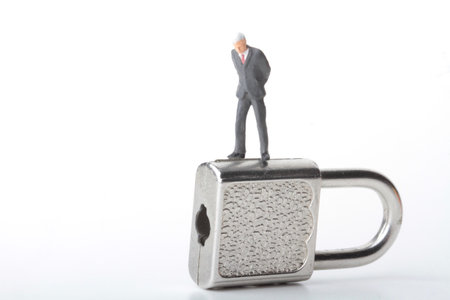 miniature businessman standing on a padlock on a white background with copy spaceの写真素材