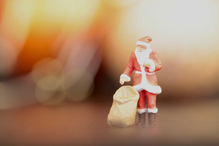 Miniature people : Santa Claus with sack of gifts on bokeh backgroundの写真素材