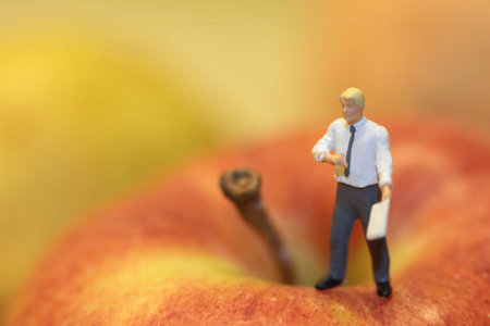 Miniature people : Businessman standing on apple with blur background.の写真素材